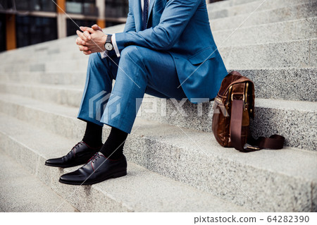 Male in a trendy suit relaxing outdoors 64282390