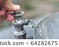 a Hand pressing the water from the park tap during the day 64282675