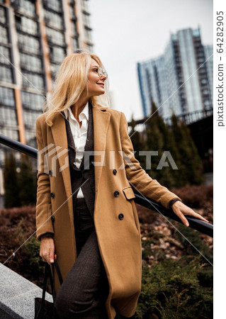 Pleased lady holding a leather tote bag Pleased lady holding a leather tote bag 64282905