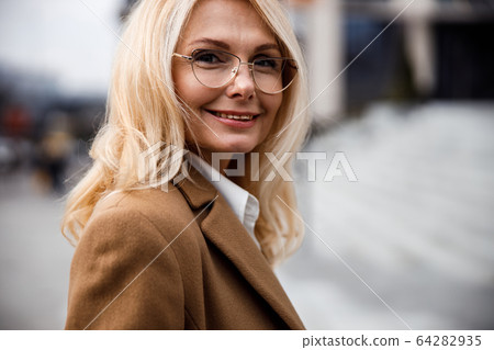 Joyous elegant lady in eyeglasses looking forward 64282935