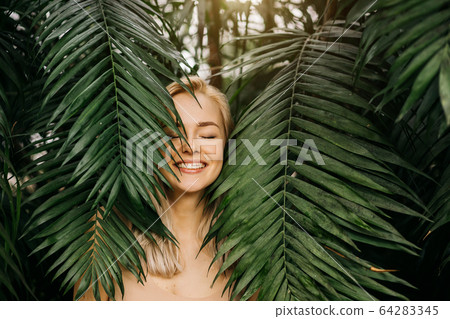 Woman in swimsuit on tropical plants background Woman in swimsuit on tropical plants background 64283345