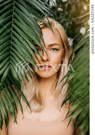 Woman in swimsuit on tropical plants background Woman in swimsuit on tropical plants background 64283346