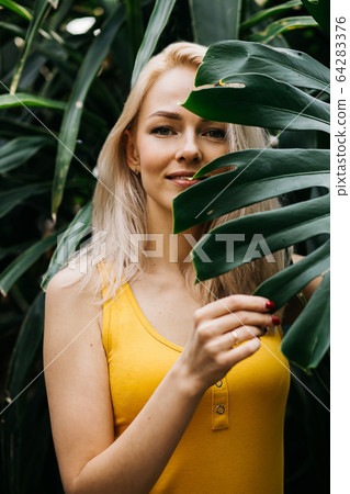 Woman in swimsuit on tropical plants background Woman in swimsuit on tropical plants background 64283376