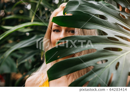 Woman in swimsuit on tropical plants background Woman in swimsuit on tropical plants background 64283414