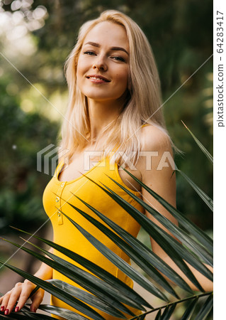 Woman in swimsuit on tropical plants background Woman in swimsuit on tropical plants background 64283417