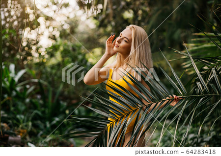 Woman in swimsuit on tropical plants background 64283418