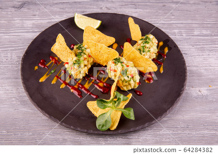 Guacamole with avocado and chopped greens, served with chips, ketchup and mustard Guacamole with avocado and chopped greens, served with chips, ketchup and mustard 64284382