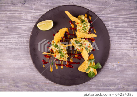 Guacamole with avocado and chopped greens, served with chips, ketchup and mustard Guacamole with avocado and chopped greens, served with chips, ketchup and mustard 64284383