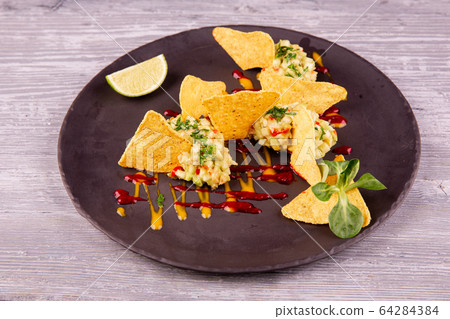 Guacamole with avocado and chopped greens, served with chips, ketchup and mustard Guacamole with avocado and chopped greens, served with chips, ketchup and mustard 64284384