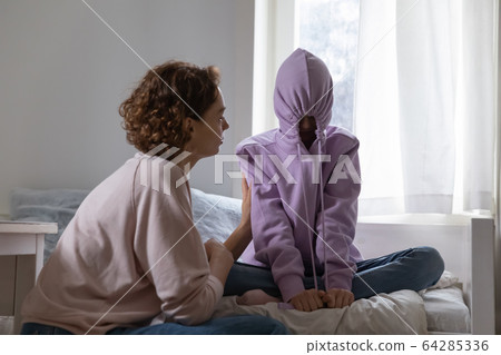 Stubborn teenage girl putting hood on avoiding talk with mom 64285336