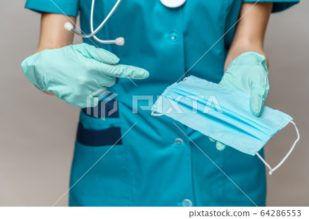 medical doctor nurse woman with stethoscope over light grey background - showing protective mask 64286553