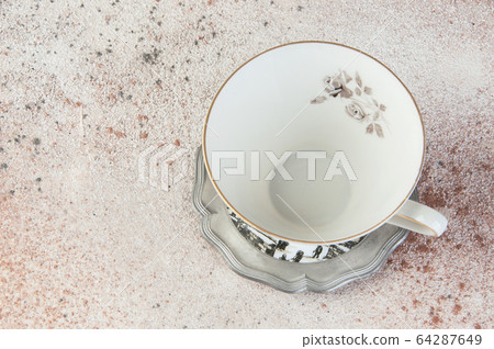 Antique tea mug on pewter coaster on concrete Antique tea mug on pewter coaster on concrete 64287649