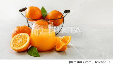 Freshly squeezed orange juice in a glass and Freshly squeezed orange juice in a glass and 64288627