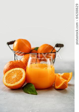 Fresh orange juice in a glass and oranges on light Fresh orange juice in a glass and oranges on light 64288629