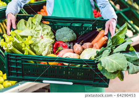 Saleslady holding box with organic vegetables in shop 64290453