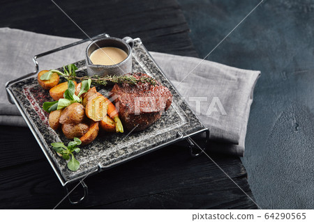 Grilled ribeye steak on stone grill on a dark background 64290565