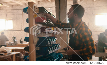 Carpentry industry - bearded man worker choosing screws on the stand 64290622