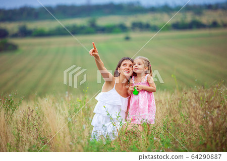 Happy mother and daughter spending time together outdoors, pointing fingers and enthusiastically looking up, with pleasure spending time in countryside Happy mother and daughter spending time together outdoors, pointing fingers and enthusiastically looking up, with pleasure spending time in countryside 64290887