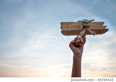 Happy kid playing with toy wooden airplane against Happy kid playing with toy wooden airplane against 64294428