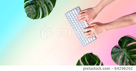 Person using a computer keyboard with tropical leaves Person using a computer keyboard with tropical leaves 64296202
