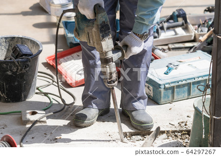 Civil engineer breaking concrete with an electric hammer 64297267