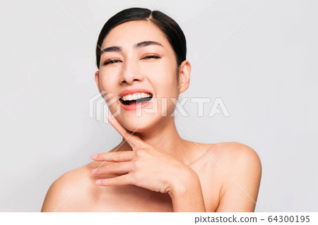 young beautiful asian woman with clean and bright skin, Cosmetic Beauty Concept,hands touch on the cheek, smiling and friendly face isolated on grey background young beautiful asian woman with clean and bright skin, Cosmetic Beauty Concept,hands touch on the cheek, smiling and friendly face isolated on grey background 64300195