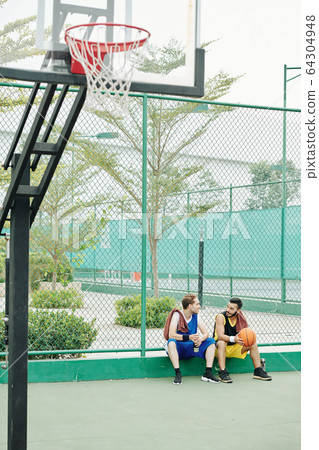 Friends resting after game of basketball Friends resting after game of basketball 64304948