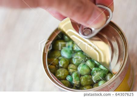 Hand open canned food in metal can on wooden Hand open canned food in metal can on wooden 64307625