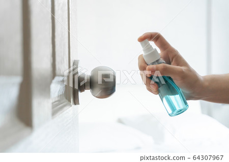 Hand applying alcohol spray to door, doorknob Hand applying alcohol spray to door, doorknob 64307967