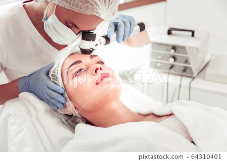 Woman having deep face cleansing visiting cosmetologist 64310401