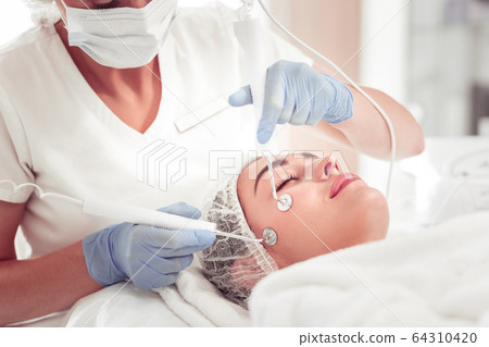 Beauty expert using new equipment for deep facial cleansing Beauty expert using new equipment for deep facial cleansing 64310420
