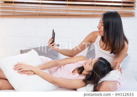 Asian lesbian couple using mobile video Asian lesbian couple using mobile video 64312633