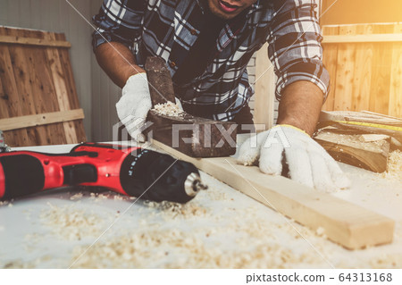Carpenter working on wood craft at workshop 64313168