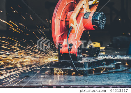 Professional mechanic is cutting steel metal. 64313317