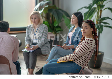 Group of people sitting in a circle close to each other and talking 64314004