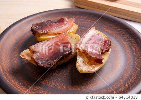 Baked potatoes with slices of bacon on wooden 64314018