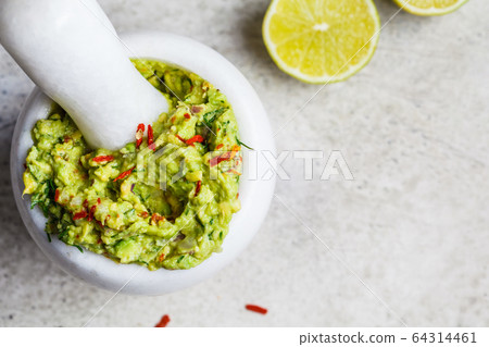 Cooking guacamole - avocado sauce in a white stone mortar Cooking guacamole - avocado sauce in a white stone mortar 64314461