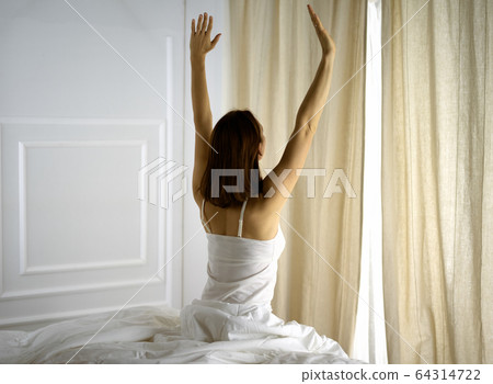 Woman stretching in bed after waking up, back view, entering a day happy and relaxed after good night sleep. Good morning and new day for brunette. Concept of Weekend, holidays Woman stretching in bed after waking up, back view, entering a day happy and relaxed after good night sleep. Good morning and new day for brunette. Concept of Weekend, holidays 64314722
