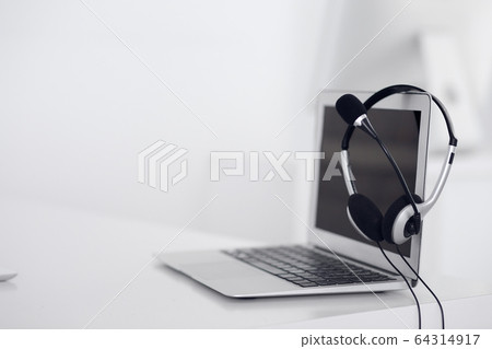 Call center and communication support, customer service help desk. VOIP headset on laptop computer Call center and communication support, customer service help desk. VOIP headset on laptop computer 64314917