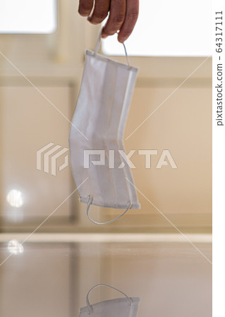 a medical mask hangs on the arm above the floor. fatigue of doctors and medical staff. fighting the covid-19 coronavirus pandemic. a worldwide problem and the tragedy a medical mask hangs on the arm above the floor. fatigue of doctors and medical staff. fighting the covid-19 coronavirus pandemic. a worldwide problem and the tragedy 64317111