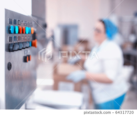 Control panel of an automatic line in production. Woman worker packs products at the factory. Industry, copy space Control panel of an automatic line in production. Woman worker packs products at the factory. Industry, copy space 64317720