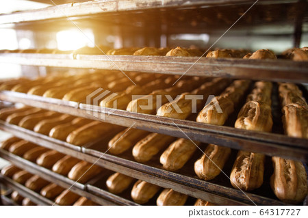 Many custard eclairs with cream filling lie on the shelves, the food industry, confectionery Many custard eclairs with cream filling lie on the shelves, the food industry, confectionery 64317727