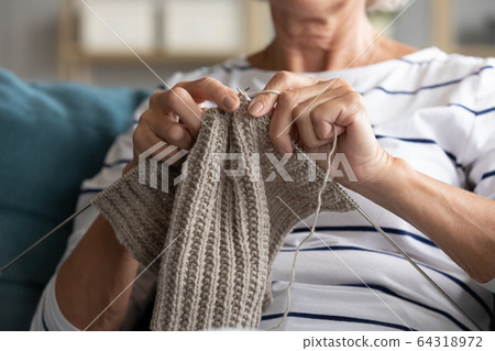 Close up older female hands holding knitting needles Close up older female hands holding knitting needles 64318972