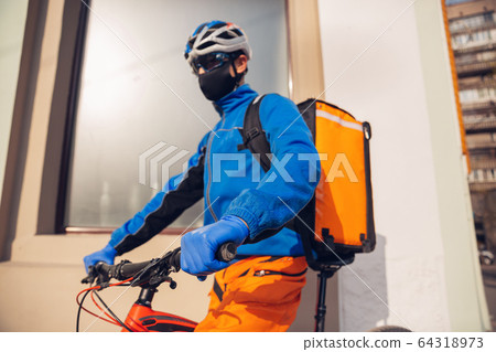 Contacless delivery service during quarantine. Man delivers food and shopping bags during isolation Contacless delivery service during quarantine. Man delivers food and shopping bags during isolation 64318973