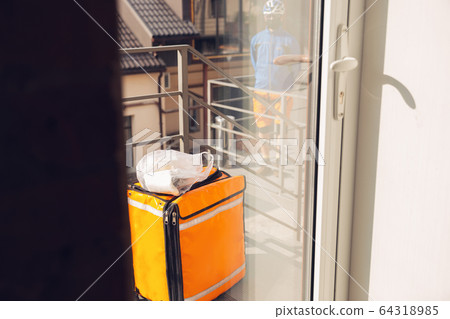 Contacless delivery service during quarantine. Man delivers food and shopping bags during isolation Contacless delivery service during quarantine. Man delivers food and shopping bags during isolation 64318985