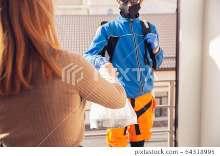 Contacless delivery service during quarantine. Man delivers food and shopping bags during isolation Contacless delivery service during quarantine. Man delivers food and shopping bags during isolation 64318995