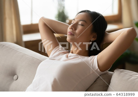 Asian woman put hands behind head resting on sofa closeup Asian woman put hands behind head resting on sofa closeup 64318999
