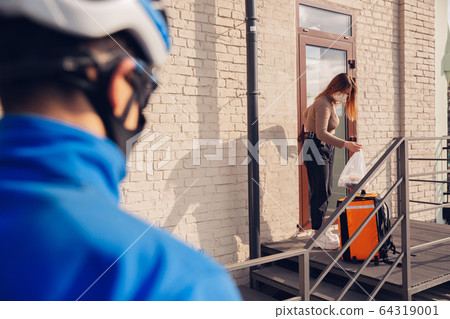 Contacless delivery service during quarantine. Man delivers food and shopping bags during isolation Contacless delivery service during quarantine. Man delivers food and shopping bags during isolation 64319001