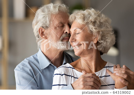 Close up older couple enjoying tender moment, hugging 64319002