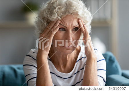 Sad mature woman touching temples close up, feeling unwell 64319007